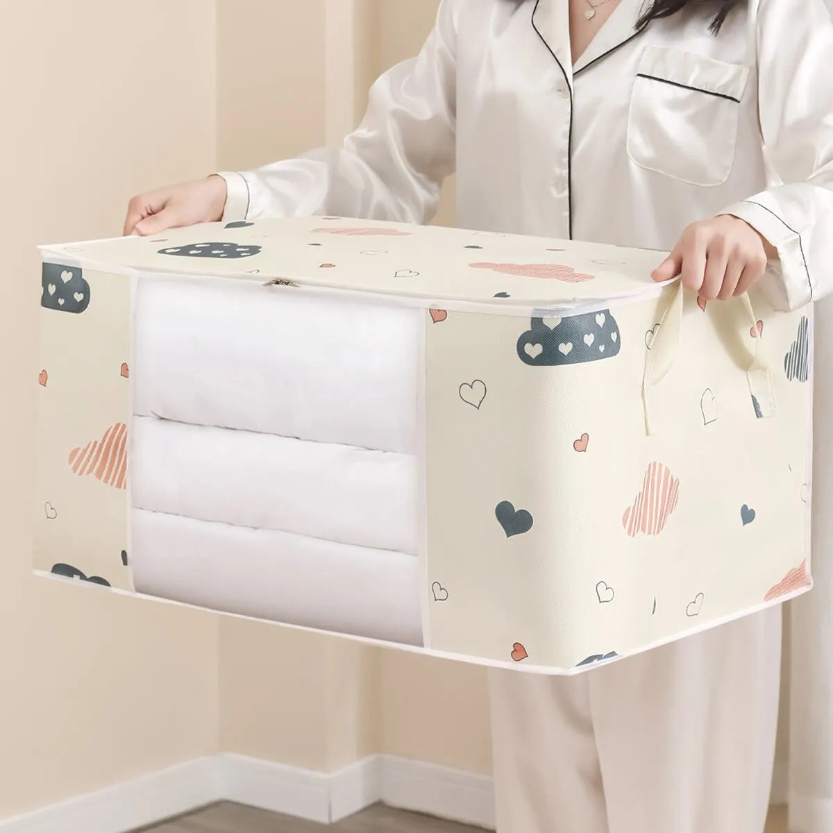 Housse de rangement RangeMalin portée par la poignée, fenêtre transparente laissant voir le linge plié à l'intérieur